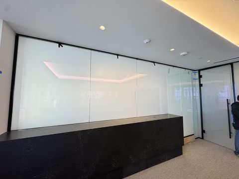 The same Santa Monica glass wall, return panels and door switched to frosted, milky white, with one of our crew at the right edge