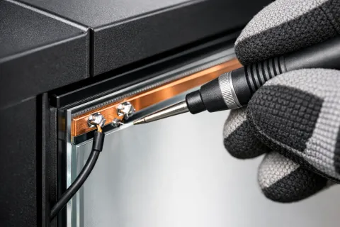 Gauzy driver diagnostic — technician testing the electrical connection and busbar voltage on a switchable smart-film panel during repair