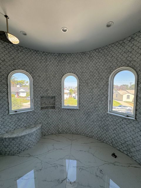A curved tiled shower in Torrance with three arched switchable windows in clear mode, looking out to the neighborhood in daylight
