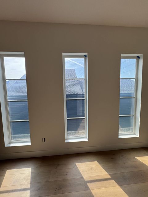 Three tall divided-lite windows in a Hollywood Hills home with switchable glass in clear mode, the neighboring rooftop visible through the panes