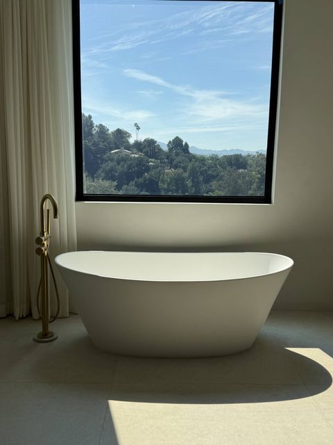 Master bathroom window above a freestanding tub at a Hidden Hills home with the switchable film powered clear, hillside views visible