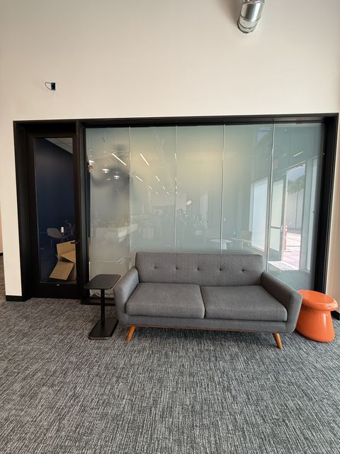 Smart glass LAX office Inglewood — multi-panel partition wall separating lounge from open office workspace