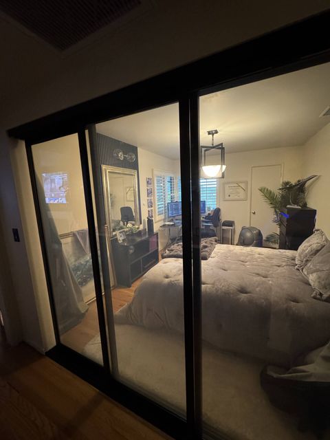 Real Smart View bedroom install in Pasadena: a black-framed switchable glass sliding partition in its clear state, showing the room beyond