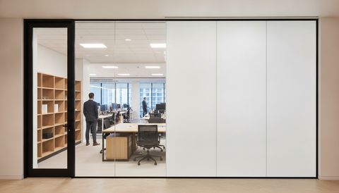 El Segundo glass-walled private office with a floor-to-ceiling entry sidelight beside a wall of switchable smart glass — half the panels crystal clear to the open floor, half switched to flat, even, milky-white frosted privacy mode
