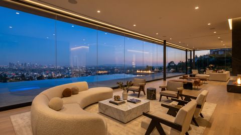Hollywood Hills modern home at dusk with a floor-to-ceiling clear switchable smart glass wall overlooking the Los Angeles city lights