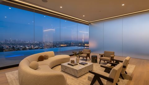 Hollywood Hills modern home at dusk with a floor-to-ceiling clear switchable smart glass wall overlooking the Los Angeles city lights — several glass panels switched to frosted privacy mode