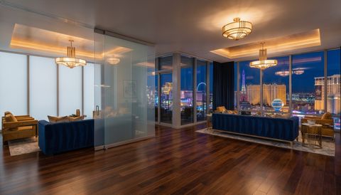 Las Vegas high-rise condo with a floor-to-ceiling clear switchable smart glass wall overlooking the Strip skyline at night — several glass panels switched to frosted privacy mode