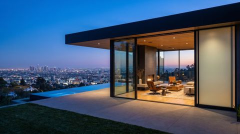 Modern Los Angeles Hills home with floor-to-ceiling clear switchable smart glass framing the LA basin and downtown skyline at dusk