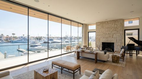 Newport Beach harbor-front home with a floor-to-ceiling clear switchable smart glass wall overlooking the marina and yachts