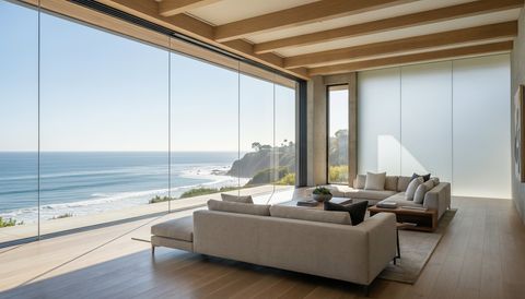 Pacific Palisades bluff-top home with a floor-to-ceiling clear switchable smart glass wall framing a Pacific Ocean view — several glass panels switched to frosted privacy mode