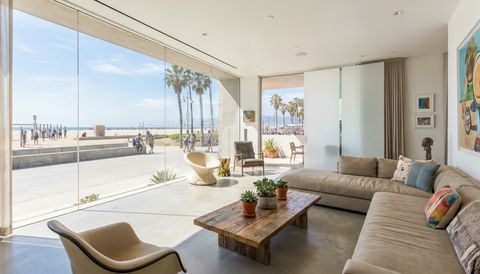 Venice Beach modern beach house with a floor-to-ceiling clear switchable smart glass wall overlooking the boardwalk and palms — several glass panels switched to frosted privacy mode