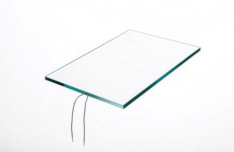 Close-up of a smart glass panel edge with two low-voltage lead wires running to a small transformer on the windowsill