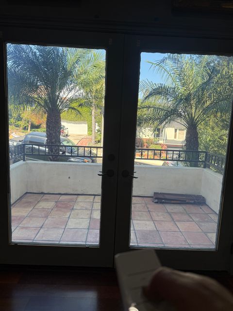 Switchable smart film on French patio doors in a Los Angeles home, clear to show the palm-lined patio beyond