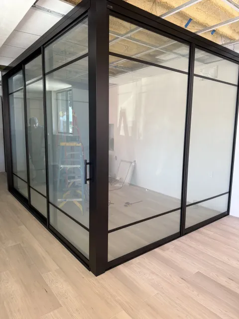 Real Smart View install: floor-to-ceiling switchable glass partitions around a corner room in the clear state, black frames, interior fully visible