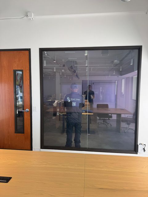 A Smart View installer beside a switchable glass office conference partition during a Newport Beach install
