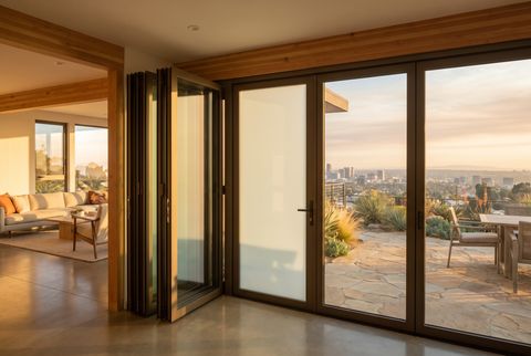 Illustration: a folding operable glass wall half open onto a terrace with a Los Angeles view, drawn with two of the closed panels switched to an even milky frost while the rest stay clear