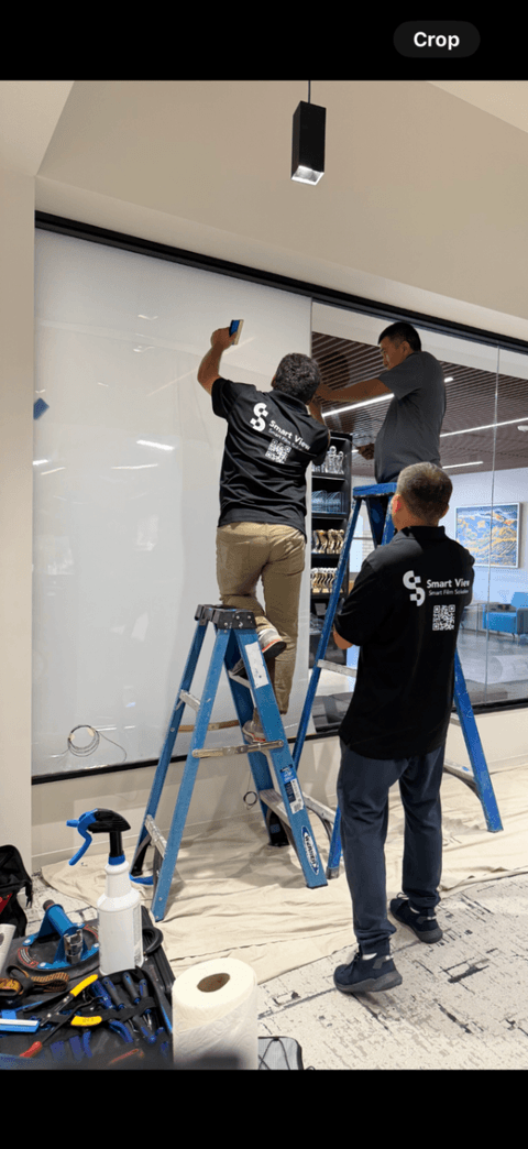 Technicians applying switchable film to a Beverly Hills conference-room glass wall