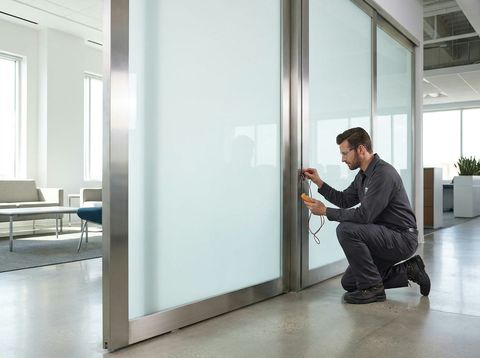 A technician diagnosing the wiring on a frosted smart-glass partition