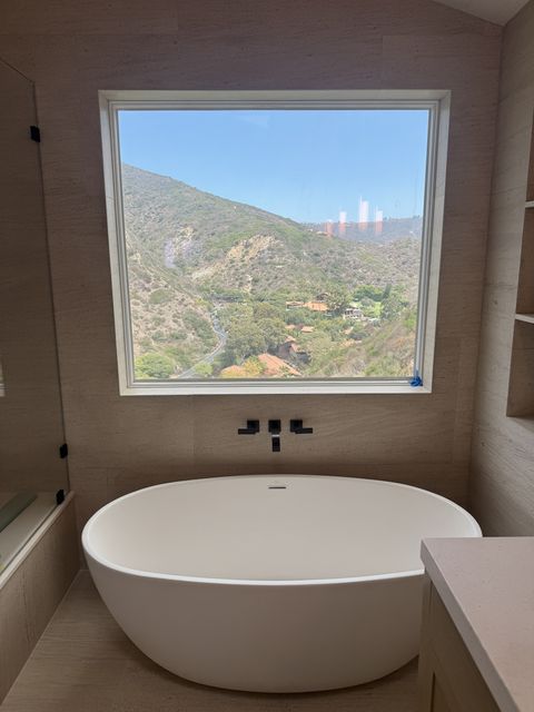 Real Smart View install in Laguna Beach: switchable smart film on an existing bathroom picture window in the clear state, showing the canyon view above a freestanding tub