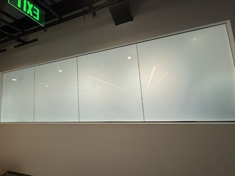 Corridor side of the Los Angeles laboratory smart film window frosted to an even milky white, fully screening the lab behind it