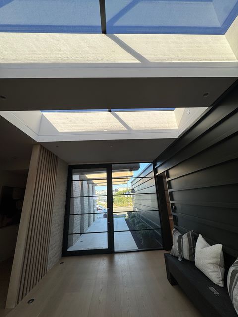 Low view down the skylit Newport Beach entry hall toward the clear glass door wall