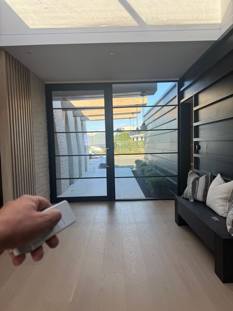 Hand holding a remote while the Newport Beach door and side panel stay clear