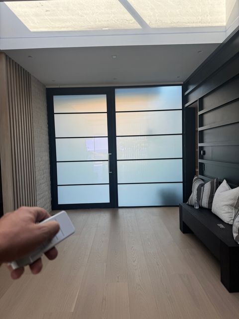 Hand holding the remote as the door and side panel switch to frosted white