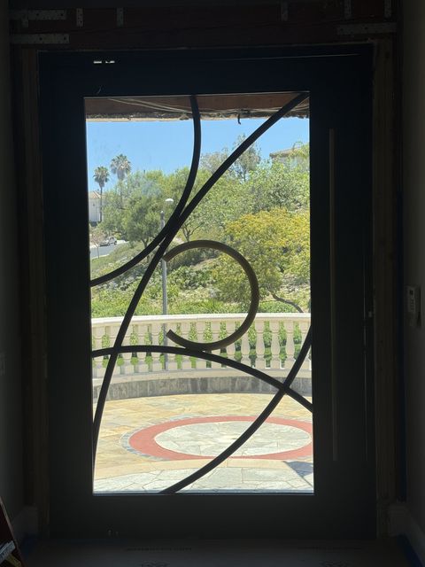 Smart film front door in Rowland Heights, the tall glass lite clear behind an ornamental wrought-iron scroll grille
