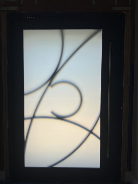 Smart film front door in Rowland Heights frosted to an even milky white for entry privacy, behind the wrought-iron scroll grille