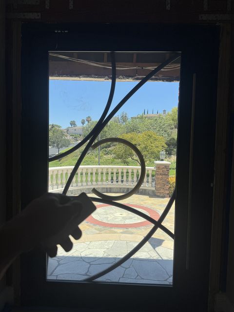 Hand holding a Smart View remote at a Rowland Heights front door, the glass lite clear with the garden beyond