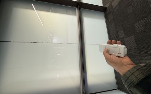 Frosted smart glass conference room panels in Carlsbad CA with the Smart View remote in hand