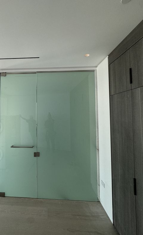 Culver City bathroom partition in frosted privacy mode, the full-height glass wall and swing door reading as one even milky-white plane