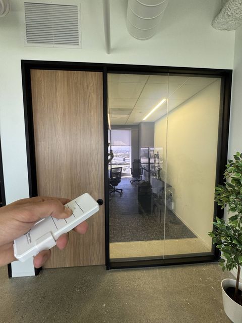Real Smart View install: a switchable glass office partition in El Segundo shown clear, with the handheld remote that flips it clear or frosted