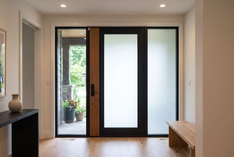 Illustration: an entry door seen from inside a foyer — the door's full-height glass lite and the narrow panel beside it switched to an even milky frost, while the glass on the other side stays clear onto a green front porch