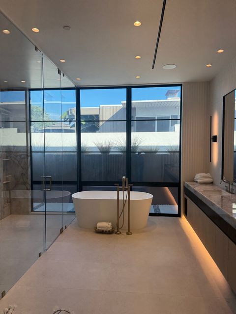 Newport Beach bathroom smart glass window clear, freestanding tub under the black steel window wall with the neighbors' upper floor in view