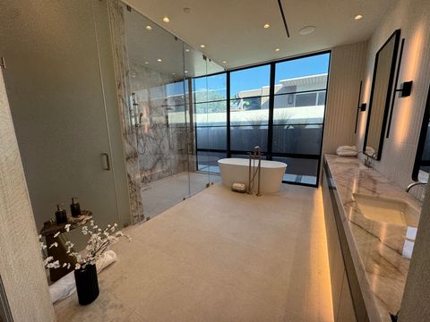 Wide view of the Newport Beach master bath, marble shower on the left, tub window clear to the sky and the neighboring rooflines