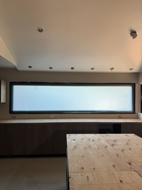 Smart glass kitchen Seal Beach — letterbox window in frosted state above lower cabinetry during construction