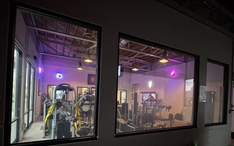 Smart glass gym windows in Ventura in clear mode, training equipment visible through the switchable glass