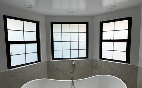 Smart glass West Covina CA bathroom windows in frosted privacy mode above a freestanding tub