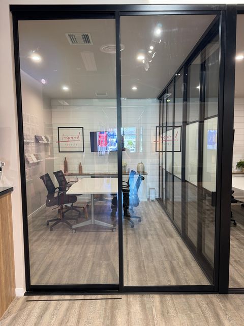Black-framed smart glass partition at the Inspire Closets design showroom in Woodland Hills, powered on and clear