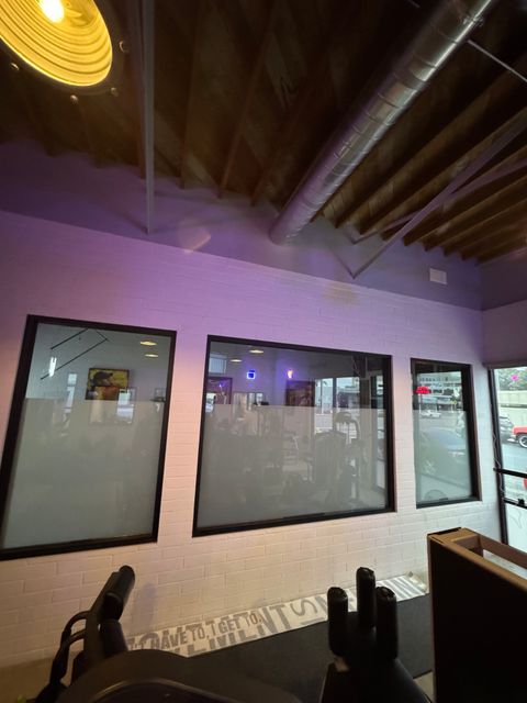 A run of switchable smart glass partition windows inside a Ventura studio, frosted for privacy under purple lighting