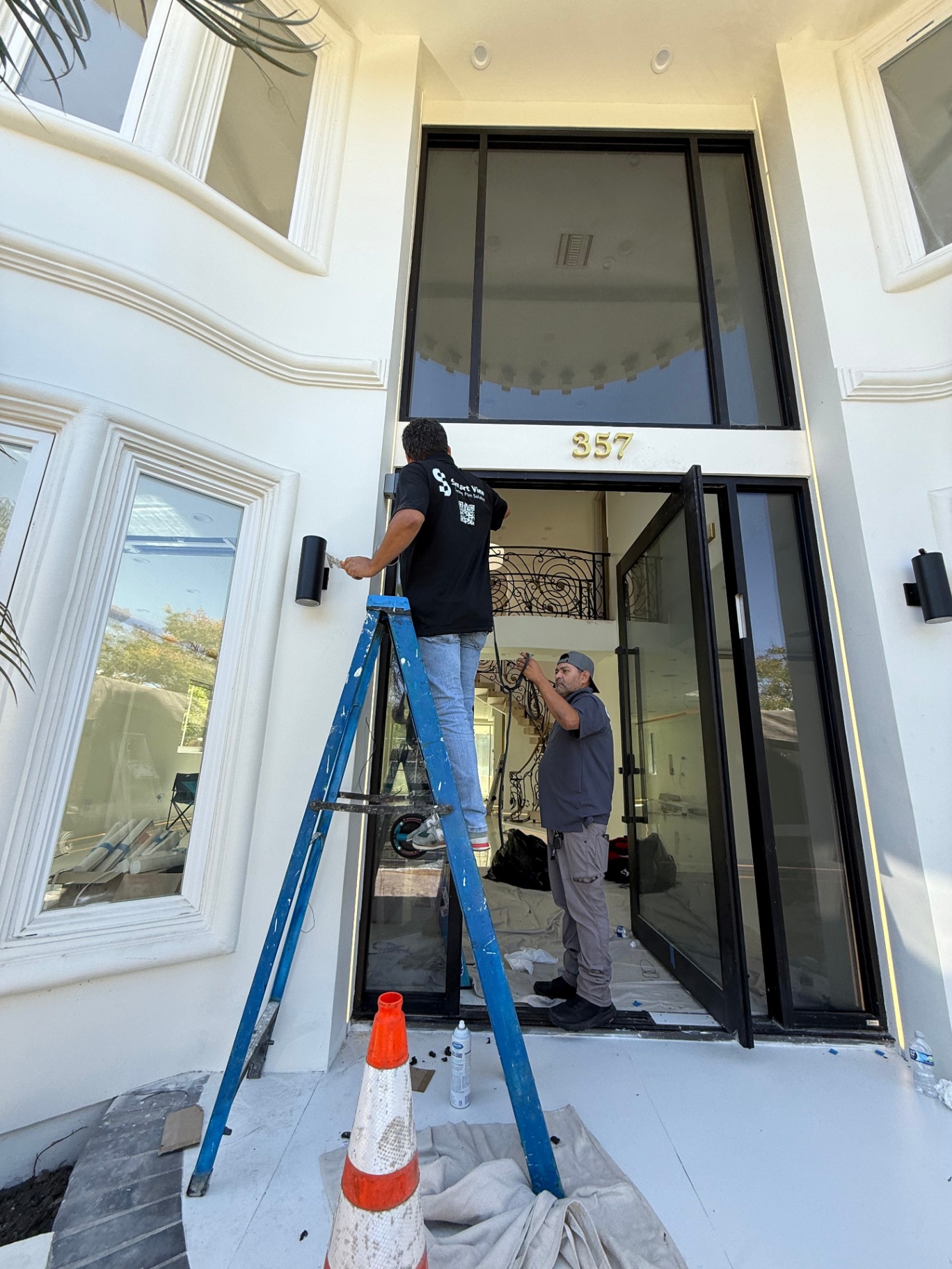 Smart glass retrofit process in progress — technicians installing Smart View switchable smart film on a glass entryway with concealed wiring planning