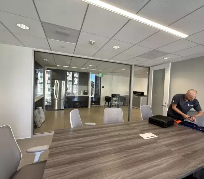 First time smart film install guide — technician preparing to apply switchable film to a modern LA conference-room glass wall